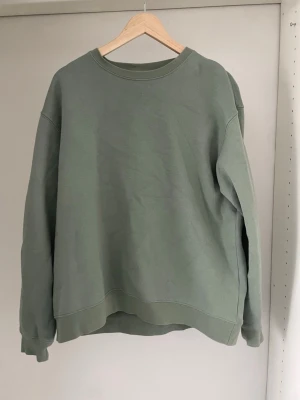 Grön sweatshirt från Zara - Säljer en enkel och stilren sweatshirt från Zara. Tröjan har rund halsringning, långa ärmar och ribbade muddar vid ärmslut och nederkant. Perfekt för en avslappnad look och passar till det mesta i garderoben.