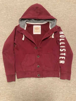 Vinröd hoodie från Hollister - Säljer en Röd Hoodie från Hollister i mycket bra skick! Förutom att den är använd så har den inga defekter. Storlek S, hör av er om frågor!