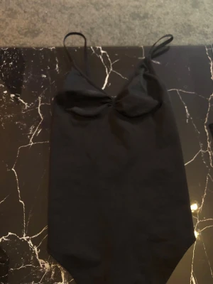 Skims dupe body - Snygg svart skims dupe body  med tunna justerbara axelband och  rynkad detalj vid bysten som formar. Klassisk och enkel design som passar perfekt till jeans eller kjol. Tillverkad i stretchigt material för skön passform men som ändå formar kroppen. 