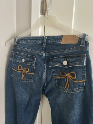 Lågmidjade jeans  - Lågmidjade jeans från Monki med rosetter på bakfickorna!! Supersnygga💞