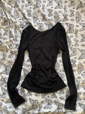 Svart långärmad topp med öppen rygg  - Säljer en svart långärmad topp med figurnära passform och öppen rygg 