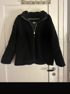 Svart teddyjacka från Newyorker - Mysig svart teddyjacka från Amisu med dragkedja framtill och hög krage. Jackan har två fickor på sidorna och är tillverkad i fluffigt teddy-material som håller dig varm. Perfekt för kyliga dagar och enkel att matcha med olika outfits. Ge gärna prisförslag och pruta med rimlighet!💖💓