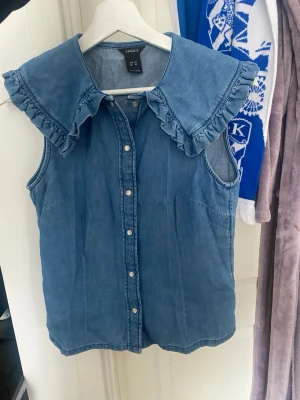 Denimblus med volang  - Super snygg unik blus i lite denimliknande material. Knappt använd! Pris går att diskutera!