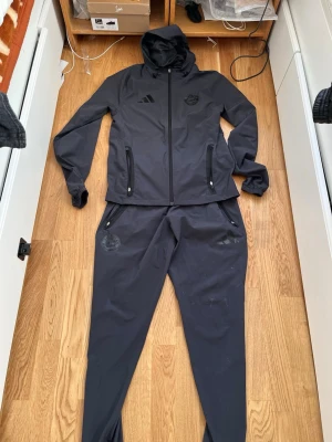 Svart Adidas Bayern München träningsset - Säljer ett svart träningsset från Adidas och Bayern München. jackan är strl Xs men passar S också och byxan är s passar M också inga problem med den köptes från zalando för 1800 kr 