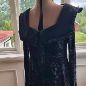 Svart sammetsklänning KILLSTAR - Svart GOTH sammetsklänning med lång ärm och stor krage med volangkant från KILLSTAR. Den är i helt nyskick, endast använd en gång. Den har en inbyggt underklänning så den är två lager. Tyget består av sammet som är "stretchy". Kragen är super söt! Nypris: 1400 kr