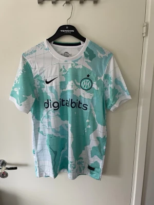 Inter Milan bortatröja 2022/23 - Snygg Inter Milan bortatröja från säsongen 2022/23 i vitt och ljusblått med världskarta-mönster. Riktigt fet tröja till sommaren passar till allt storlek L men passar till dig som har M med 