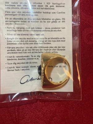 Gynning Jewelry Devine Eye Ring 16,5 925 silver guldpläterat. - Säljer en unik Devine Eye-ring från Carolina Gynning Jewelry i guldpläterat silver. Ringen har ett ögonmotiv med en svart sten i mitten och gnistrande cubic zirconia runtom. Statement piece som verkligen sticker ut och ger cool edge till din stil. Nyvara! Matchande armband i äkta silver finns under mina övriga auktioner.