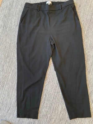 Svarta kortare kostymbyxor med slits - Object kortare byxor svarta strl 44, modell objlisa slim pant noos. Byxorna har resår i midjan och en liten slots längst ner vid benet.  Använda och lite noppriga i övrigt i bra begagnat skick.  Mått Midjan: ca 45 cm Längd från grenen och ner: ca 66 cm  63% polyester, 32% viskos och 5% elastan   Kommer från ett djur och rökfritt hem 