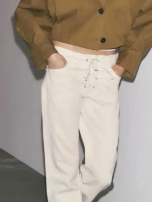 Vida vita jeans med snörning - Säljer ett par trendiga vita jeans med vida ben och snygg snörning framtill i midjan. Jeansen har en avslappnad passform och är tillverkade i ett klassiskt denimtyg. Perfekta för dig som vill ha en unik twist på dina basjeans.