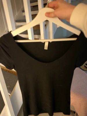 Svart t-shirt från H&M - En enkel svart t-shirt från H&M med rundad v-ringning och korta ärmar. Perfekt basplagg att matcha till olika outfits. Tillverkad i mjukt bomullsmaterial för skön känsla.