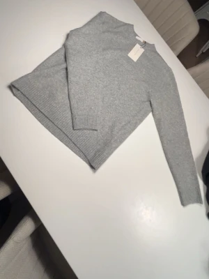 Ljusgrå stickad tröja från Pier One - Mysig ljusgrå stickad tröja från Pier One i enkel och stilren design. Tröjan har rund halsringning, långa ärmar och ribbade muddar vid ärmslut och nederkant. Perfekt basplagg i garderoben för dig som gillar minimalistisk stil. 