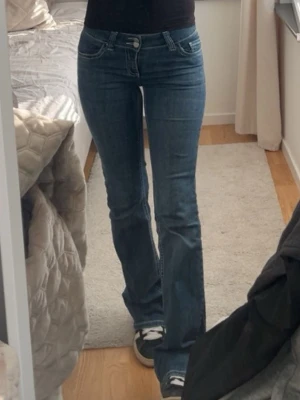 Nelly jeans  - Säljer ett par blå bootcut jeans med vita broderade detaljer på bakfickorna. Lågmidja, är 170. Lite små defekter som man ser på bild 2,3 annars bra skick! 