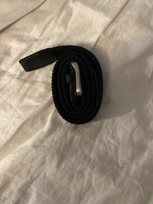 Svart flätat bälte Jack & Jones - Snyggt svart flätat bälte från Jack & Jones med silverfärgat spänne och detaljer i skinn. Perfekt accessoar för att lyfta din outfit och funkar till både jeans och kostymbyxor. Klassisk design som passar till det mesta.