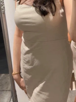 Beige klänning i bomull - Säljer en stilren beige klänning med smala axelband och figurnära passform. Klänningen är ärmlös och har en enkel, rak design som ger en clean look. Perfekt för dig som gillar minimalistisk stil.