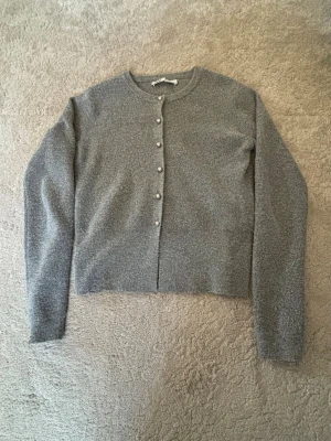 Grå kofta med pärlknappar - Mysig grå kofta med rund halsringning och långa ärmar. Koftan har fina pärlknappar framtill och är tillverkad i ett mjukt, fluffigt material. Enkel och stilren design som passar till det mesta.🤗Skriv privat för fler bilder❤️