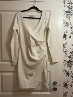 Vit omlottklänning med lång ärm - Perfekt klänning till studenten :) Snygg vit omlottklänning från Gina Tricot med lång ärm och v-ringning. Klänningen har en figurnära passform och en lätt drapering i sidan. Använd en gång på min studentmottagning 