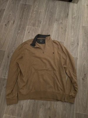 Beige quarter zip från Polo Ralph Lauren - Snygg beige quarter zip-tröja från Polo Ralph Lauren med klassisk broderad logga på bröstet. Tröjan har hög krage med dragkedja och ribbade muddar vid ärmslut och nederkant. Perfekt för lager på lager och stilrena outfits. priset kan diskuteras