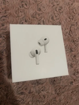 Apple AirPods Pro trådlösa hörlurar - Säljer ett par Apple AirPods Pro i vitt. De är in-ear hörlurar med stilren design och silikonproppar för bra passform. Kommer i originalförpackning med minimalistisk look. Perfekta för dig som vill ha grymt ljud och smidig anslutning till iPhone.