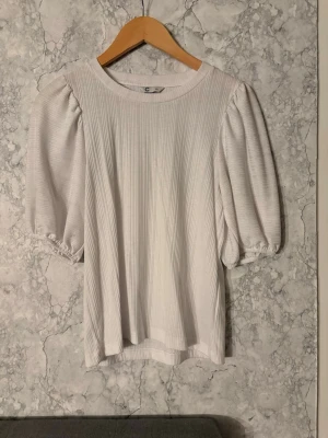 Vit ribbad topp med puffärm - Snygg vit topp i storlek xs och den är helt oanvänd.