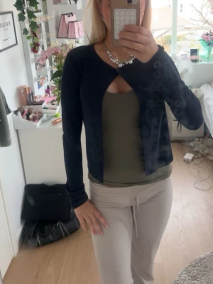 Mörkblå cardigan från Gina Tricot - Trendig mörkblå cardigan från Gina Tricot med lång ärm och öppen front som knäpps med en knapp upptill. Kortare modell som passar perfekt över linne eller topp. Tunn och mjuk kvalitet, enkel att styla till olika outfits.