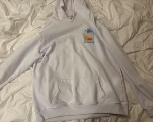 Vit hoodie från Casablanca - Säljer en vit hoodie från Casablanca med färgglad grafisk print av ett fönster och texten 'Casa Blanca' på ryggen och bröstet. Hoodien har huva och magficka, samt ribbade muddar. Perfekt för dig som gillar streetwear och snygga detaljer. Kan gå ned i pris vid snabb affär.