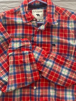 Rutig skjorta från B.B. Company - Säljer en färgglad rutig skjorta från B.B. Company i rött, blått, grönt och vitt. Skjortan har lång ärm, klassisk krage och knappar framtill. Detalj med broderad svart björn på bröstet. Perfekt för dig som gillar en avslappnad men ändå stilren look.