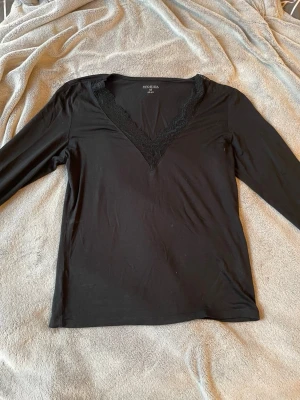 Svart långärmad topp med spets - Svart långärmad topp som är liknar Intimissmi tröjan. Tillverkad i mjukt material som känns skönt mot huden. Perfekt för dig som gillar stilrena plagg med en twist.