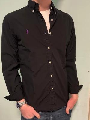 Svart Ralph Lauren skjorta – M Slim Fit - Säljer denna stilrena och snygga svarta Ralph Lauren skjorta. Skjortan är i  bra skick. Modellen är M slim fit. Har du några frågor? Tveka inte att höra av dig. Allt gott från Deluxe garderoben ⭐️ 