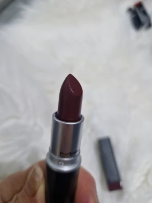 MAC Diva 603 mörkrött läppstift - MAC Diva 603 är ett mörkrött läppstift med matt finish. Hylsan är svart med silverdetaljer och klassisk MAC-design. Färgen är djup vinröd, perfekt för att skapa en statement-look. Läppstiftet har en klassisk form som gör det enkelt att applicera.