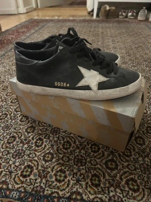 Svarta GGDB sneakers med vit stjärna - Säljer ett par svarta sneakers från Golden Goose med vit stjärndetalj på sidan. Pris ej hugget i sten skriv vid frågor 
