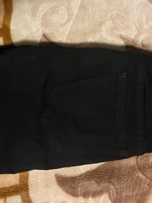 Svarta tighta jeans med hög midja - Säljer ett par svarta tighta jeans från Kappahl  med hög midja. Jeansen har klassisk femficksdesign och är tillverkade i stretchigt material för skön passform. Perfekta till en avslappnad eller trendig look. Helt nya 