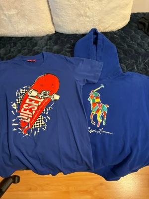 Blå t-shirt med skateboardtryck och polo hoodie - Säljer en blå t-shirt från Vans med ett stort skateboardtryck i rött, vitt och svart på framsidan. T-shirten har rund hals och korta ärmar, perfekt för dig som gillar streetwear och skatekultur. Vill du ha en av dem skriv till mig för priset av en.