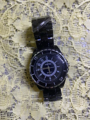 Svart Dam  klocka  - Stilren svart klocka  med rund urtavla och tydliga vita siffror. Klockan har ett svart länkarmband i metall och klassisk spännesstängning. Perfekt accessoar för dig som gillar en clean look. Helt ny med nya batteri 