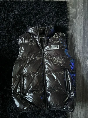 Svart glansig dunväst från Dsquared2 - Tjena säljer nu min väst från dsquared2 då den är för stor för mig. Köpte den på Season man i Jönköping så har kvitto på den. Väldigt fin men ända tråkiga är att den är lite sönder på ett ställe (kolla sista bild). Men annars är den väldigt fin. 