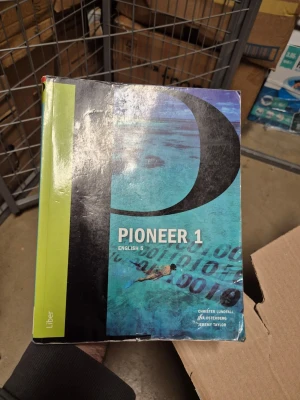 Pioneer 1 English 5 kursbok - Pioneer 1 English 5 är en kursbok i engelska med blå och svart framsida, stor bokstav P och grönt fält på sidan. Boken är skriven av Christer Lundfall, Jan Österberg och Jeremy Taylor. Perfekt för gymnasiekurser i engelska.