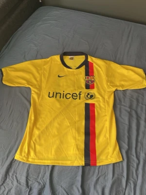 Gul FC Barcelona Messi tröja - Snygg gul FC Barcelona matchtröja från Nike med Messi och nummer 10 på ryggen. Tröjan har klubbmärke, Unicef-logga och en vertikal röd-blå rand på framsidan. Perfekt för dig som älskar fotboll och vill representera Barca.