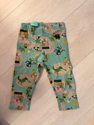 Färgglada leggings Polarn O. Pyret 98 - Superfina leggings från Polarn O. Pyret i storlek 98 med lekfullt djurmönster i grönt, gult och blått. Mjukt och stretchigt material med justerbar midja för extra komfort. Perfekta för bus och lek!