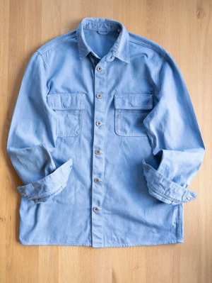 Ljusblå overshirt med fickor, size L - Snygg ljusblå overshirt i bomull med två stora bröstfickor och knappar framtill. Skjortan har klassisk krage och långa ärmar, perfekt att bära öppen eller stängd för en avslappnad look.