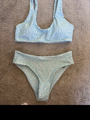 Blommig ljusblå bikini från SHEIN - Supersöt ljusblå bikini från SHEIN med vita små blommor över hela. Sportig topp med breda axelband och klassiska bikinitrosor. Perfekt för strandhäng eller poolparty! Materialet är mjukt och stretchigt syntet som torkar snabbt.