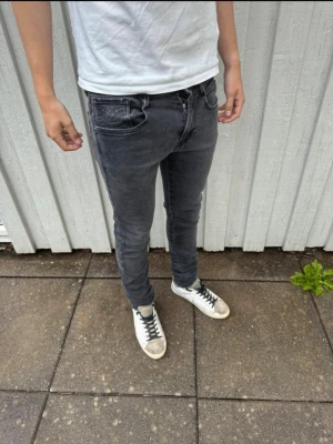 Mörk gråa Replay Anbass jeans - Säljer ett par skit snygga Replay anbass jeans med snygga sömdetaljer på bakfickorna. Jeansen har klassisk femficksmodell och smal passform som sitter tight hela vägen ner. Perfekta till en avslappnad streetstil och funkar året runt. 29/31