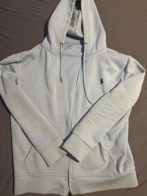 Ljusblå hoodie från Ralph Lauren - Hoodie från raulph lauren. Färgen har tyvärr fadeat lite därav det billiga priset..