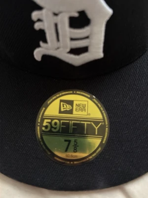 Svart New Era 59FIFTY keps - Säljer en svart New Era 59FIFTY keps med broderad vit Detroit Tigers-logga framtill och New Era-logga på sidan. Klassisk flat brim och sticker kvar på skärmen. Tillverkad i ett slitstarkt tyg som håller formen snyggt. Har använt den i några dagar.