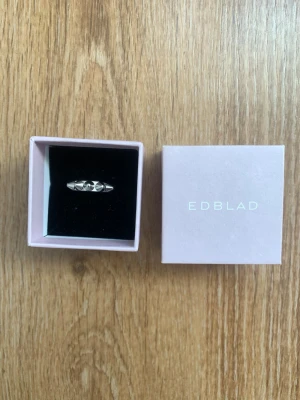Silverfärgad ring från Edblad - Snygg silverfärgad ring från Edblad med geometriska nitar som ger en cool och modern look. Ringen har en slät yta och kommer i original ask. Perfekt accessoar för att lyfta din outfit.
