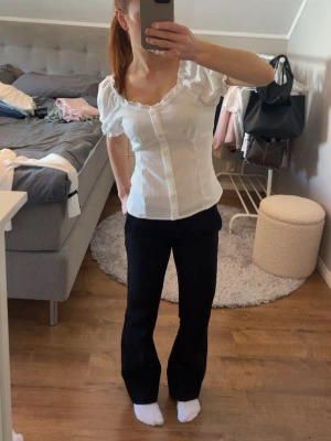 Vit blus med puffärm och knappar - Söt vit blus med puffärmar och v-ringad hals. Står ej stolen men passar xs/s. Blusen har knappar framtill och lätt ribbad struktur som ger en feminin look. Perfekt att styla med både jeans och kjol för en trendig outfit.
