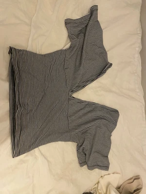 Randig offshoulder topp - Snygg svartvit randig offshoulder topp med vida ärmar. Perfekt för dig som vill ha en trendig och bekväm stil. Toppens material känns mjukt och stretchigt, vilket gör den skön att bära hela dagen.