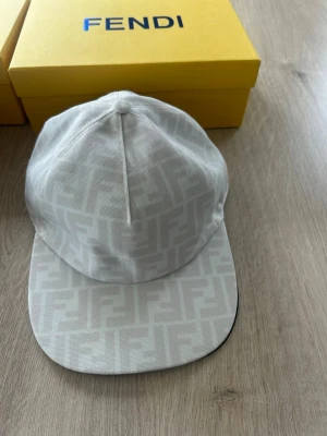 Vit keps från Fendi med FF-mönster - Vit Fendi-keps – Helt ny! 🤍🔥  Säljer en stilren och exklusiv vit Fendi-keps i mycket snygg design med det klassiska FF-mönstret. Kepsen är helt ny och i toppskick.  ✔ Justerbar storlek – passar de flesta ✔ Bekvämt material med hög kvalitet ✔ Tidlös och exklusiv design ✔ Perfekt för både vardag och finare tillfällen  Pris: 900  OBS: Kan tänka mig att sänka priset något vid snabb och smidig affär.  Först till kvarn gäller – skicka meddelande vid intresse! 📩