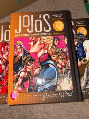 Jojo's Bizarre Adventure Golden Wind - Säljer fyra volymer av Jojo's Bizarre Adventure Part 5: Golden Wind. Böckerna har hårda omslag med färgstarka illustrationer och manga-inspirerad design. Perfekt för dig som gillar actionfylld och unik skönlitteratur med animekänsla.