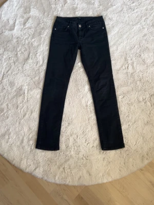 Svarta skinny jeans med låg midja - Snygga svarta skinny jeans med låg midja och klassisk femficksdesign. Jeansen har smal passform och raka ben.