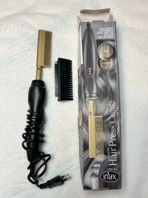 Elektrisk värmekam - OANVÄND. Elektrisk värmekam  med svart handtag och guldfärgad kamdel. Perfekt för att platta och styla håret. Medföljer även en svart plastkam. Kamdelen är i metall och handtaget i plast, med sladd för elanslutning. 