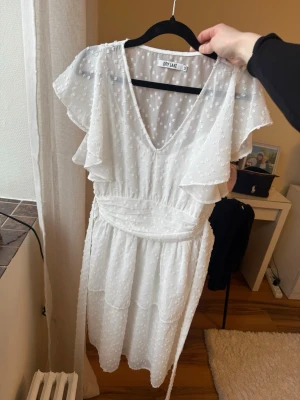 Vit klänning från Nelly  - Söt vit sommarklänningfrån nellly  med volangärmar och v-ringning. Perfekt till studenten💙💛Klänningen har ett diskret prickigt mönster, knytband i midjan och är tillverkad i ett lätt, luftigt material. Perfekt för sommarens alla tillfällen🩷 